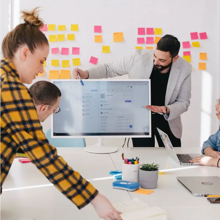 Woman pointing at a screen during a collaborative meeting with colleagues